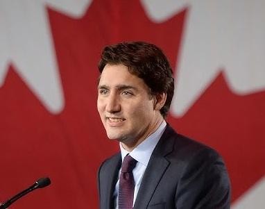 Justin Trudeau w koszulce Montreal Canadiens, entuzjastycznie kibicujący na meczu hokejowym, z widocznym tłem lodowiska i fanów.