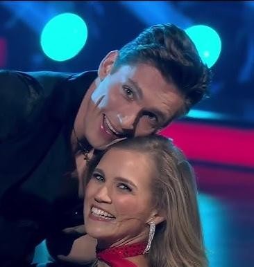Agnieszka Kaczorowska z uśmiechniętymi córkami, Emilią i Gabrielą, w ciepłej, rodzinnej scenerii, ukazująca matczyną radość i więź.