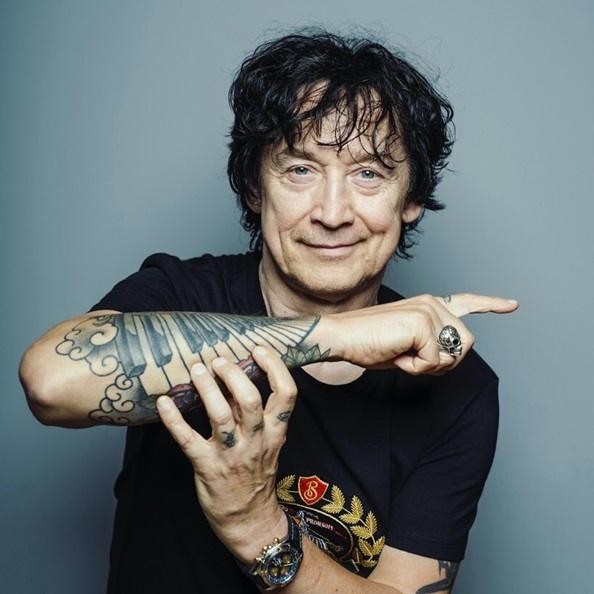 Alt: Jan Borysewicz grający na gitarze elektrycznej podczas koncertu Lady Pank, w dynamicznym ujęciu scenicznym.