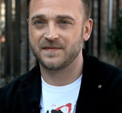 Mateusz Gessler podczas gotowania w nowoczesnej kuchni, skupiony na przygotowaniu dania.