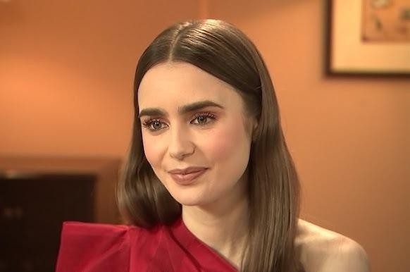 Lily Collins na planie filmowym, śmiejąca się, z rozmytym tłem sugerującym produkcję filmową.