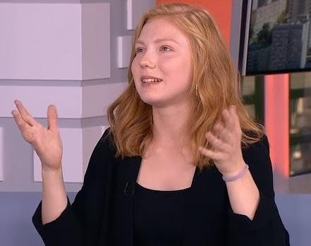 Edyta Torhan na scenie teatralnej, w ciepłym świetle, zamyślona, na tle subtelnych elementów scenografii, odzwierciedlająca jej zaangażowanie w sztukę.