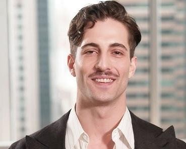 Damiano David podczas występu na scenie, w charakterystycznym stroju, z dynamicznym oświetleniem i rozmytym tłem publiczności.