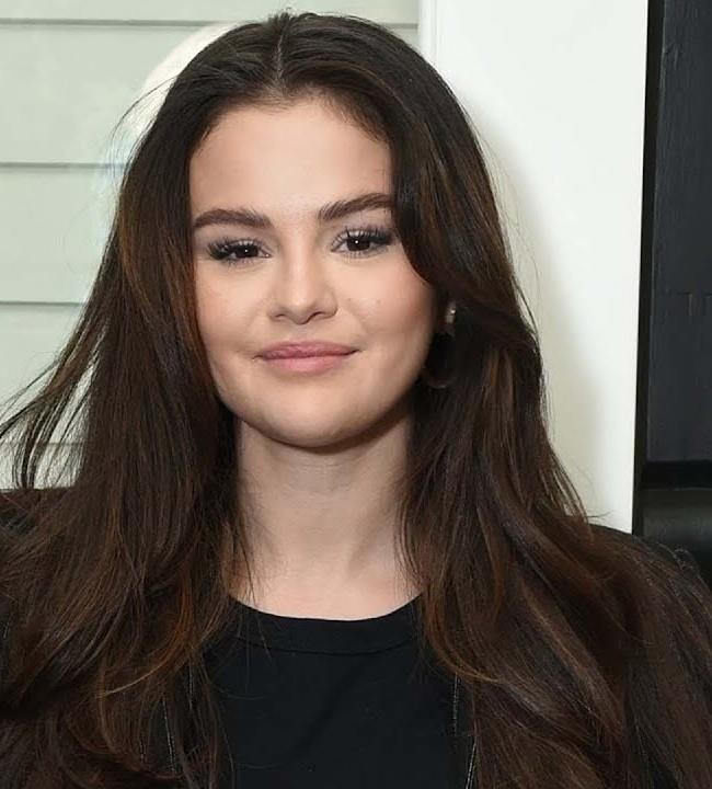 Selena Gomez podczas akcji charytatywnej, uśmiechnięta i zaangażowana, symbolizująca jej poświęcenie dla spraw społecznych.
